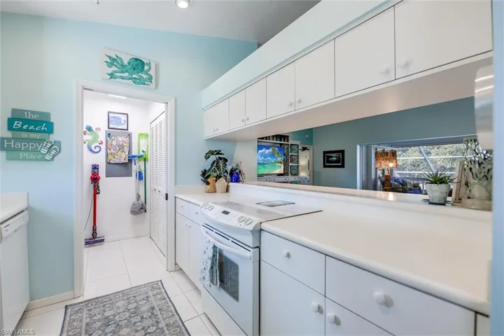 Kitchen featuring white appliances, white cabinetry, light countertops, and light tile patterned floors