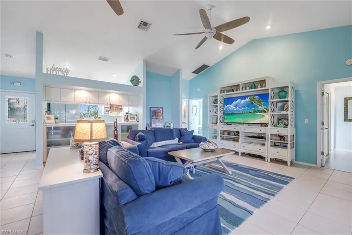 Living room with light tile patterned floors, high vaulted ceiling, a ceiling fan, and recessed lighting