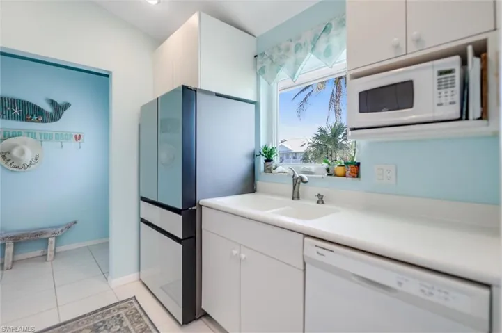 Kitchen featuring light countertops, white appliances, white cabinets, and light tile patterned floors
