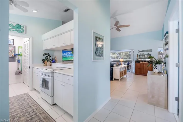 Kitchen featuring ceiling fan, white cabinets, electric range, and light tile patterned floors