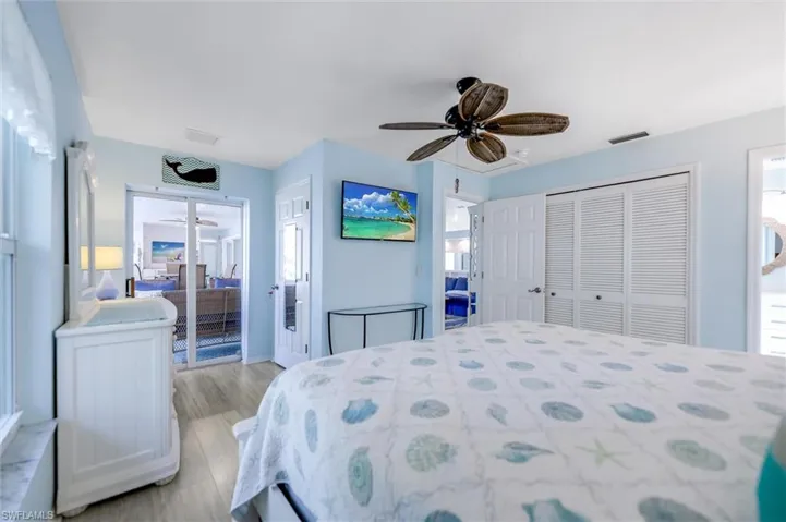 Bedroom featuring multiple closets, a ceiling fan, multiple windows, and light wood finished floors