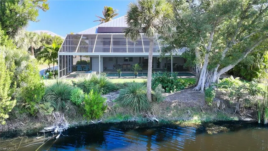 Rear view of house with a sunroom, a swimming pool, and a water view