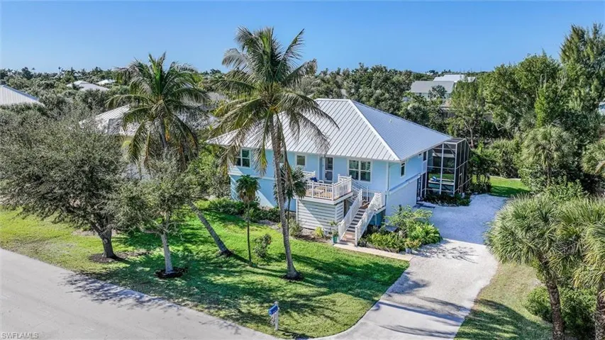 View of front of property featuring stairway, driveway, a front yard, a metal roof, and a lanai