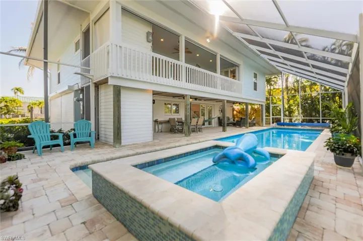 Back of house with a patio area, an in-ground hot tub, ceiling fan, a balcony, and a covered pool
