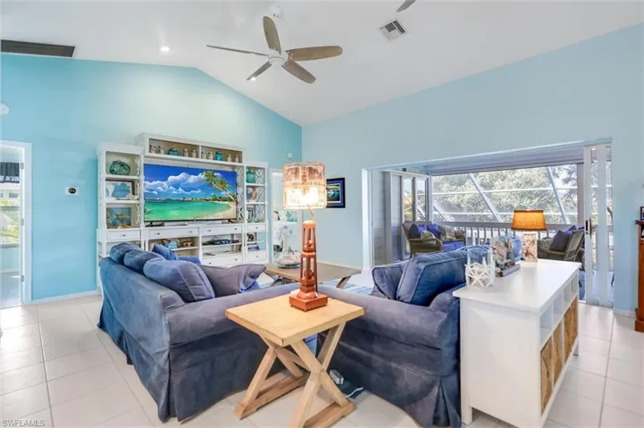 Living area with light tile patterned floors, a ceiling fan, and high vaulted ceiling