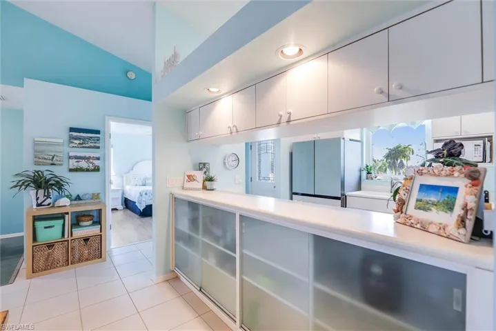 Kitchen featuring freestanding refrigerator, lofted ceiling, light countertops, and light tile patterned floors
