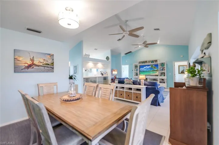 Tiled dining area featuring vaulted ceiling and ceiling fan