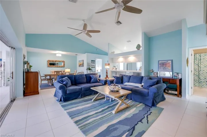 Living room with light tile patterned flooring, high vaulted ceiling, and a ceiling fan
