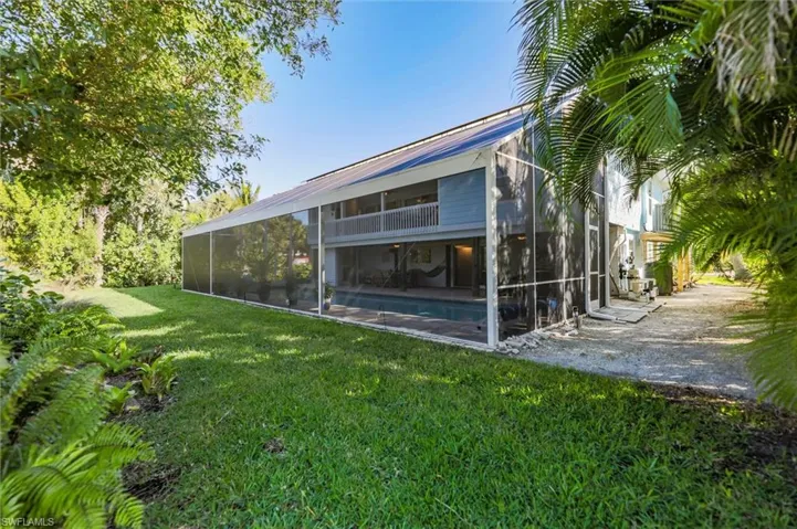 Back of house featuring a lanai, a yard, a sunroom, and an outdoor pool
