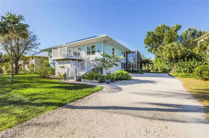 View of front of house featuring stairway, driveway, a front lawn, a lanai, and a deck