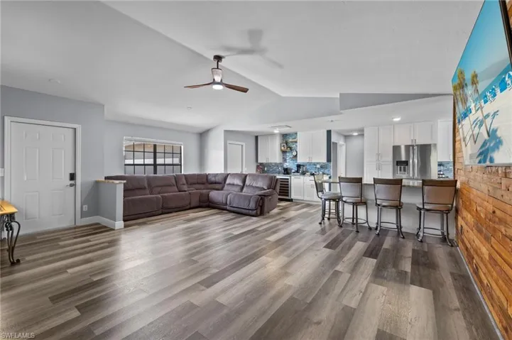 Living room featuring hardwood / wood-style flooring, ceiling fan, and vaulted ceiling
