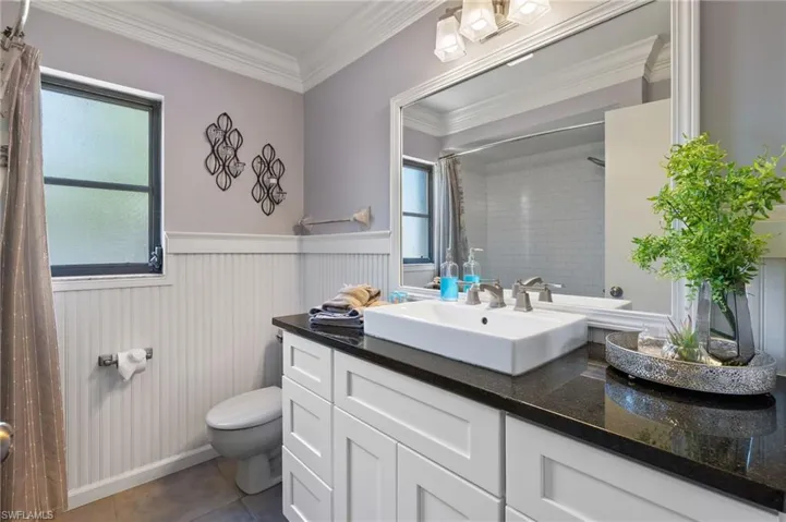 Bathroom featuring tile flooring, vanity, toilet, and crown molding