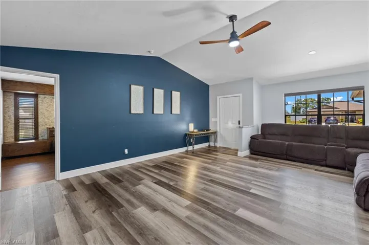 Living room featuring ceiling fan, lofted ceiling, and hardwood / wood-style flooring