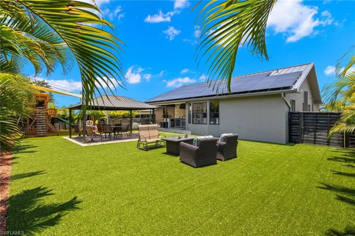 Rear view of house featuring a patio area, a lawn, solar panels, a gazebo, and an outdoor living space