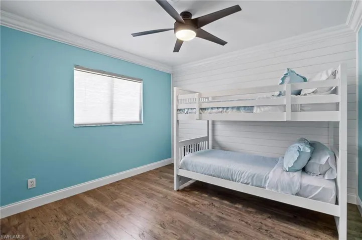 Bedroom featuring crown molding, dark wood-type flooring, and ceiling fan