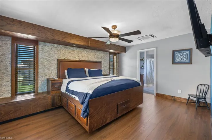 Bedroom featuring ceiling fan, ensuite bath, and dark hardwood / wood-style flooring