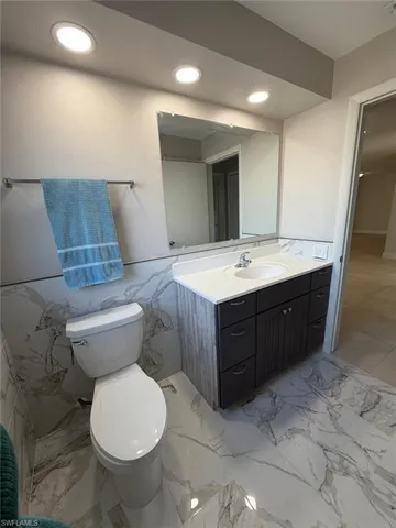 Bathroom with vanity, wainscoting, tile walls, and recessed lighting