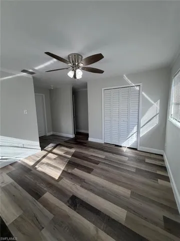 Unfurnished living room featuring dark wood finished floors and ceiling fan