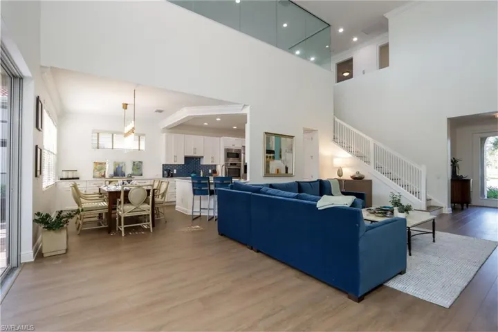Living area with a towering ceiling, stairs, and light wood-style flooring