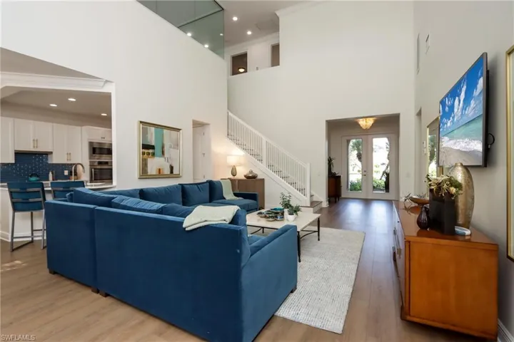 Living area featuring stairway, light wood finished floors, a high ceiling, french doors, and recessed lighting