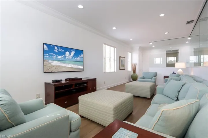 Living room with crown molding, wood finished floors, and recessed lighting