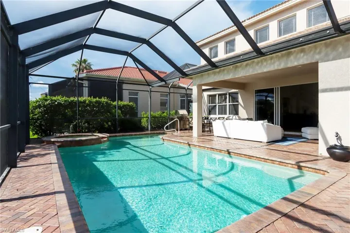 View of pool featuring a patio area, a pool with connected hot tub, grilling area, and glass enclosure