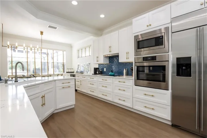 Kitchen featuring built in appliances, crown molding, tasteful backsplash, white cabinets, and recessed lighting