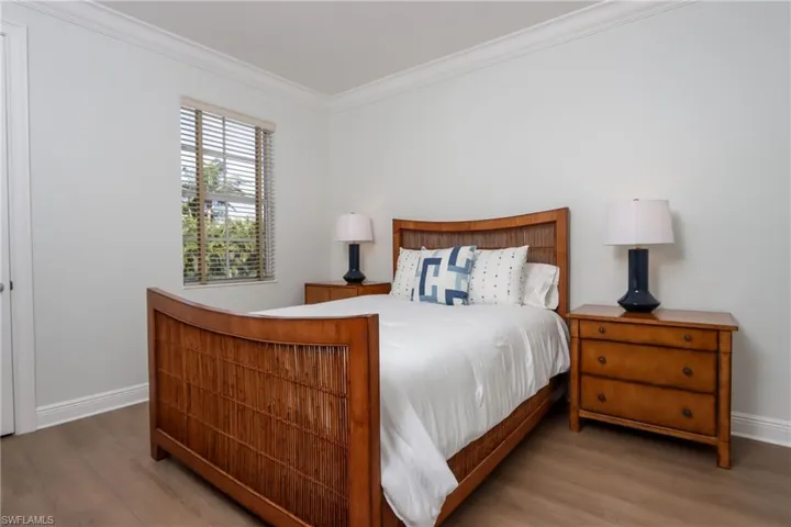Bedroom with wood finished floors and ornamental molding
