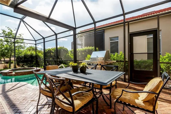 View of patio / terrace with glass enclosure, area for grilling, a pool with connected hot tub, and outdoor dining space