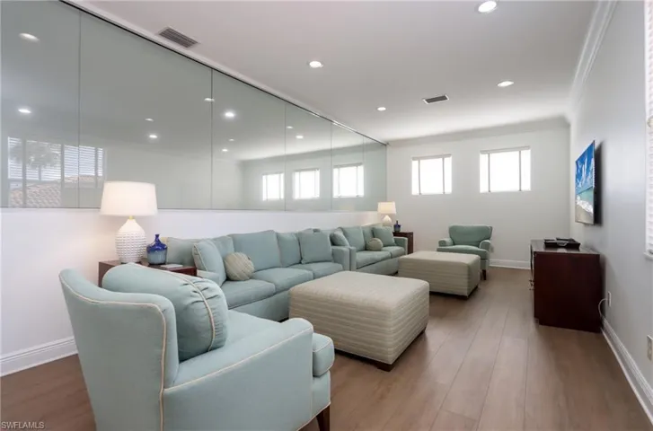 Living room with ornamental molding, wood finished floors, and recessed lighting