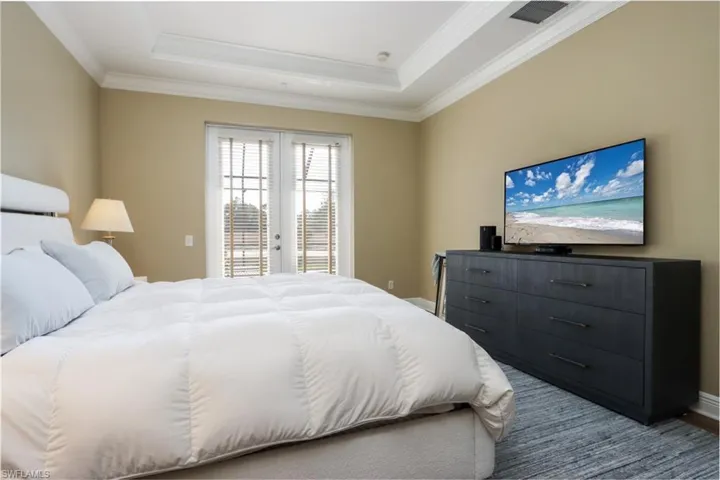 Bedroom featuring a tray ceiling, access to exterior, ornamental molding, and french doors