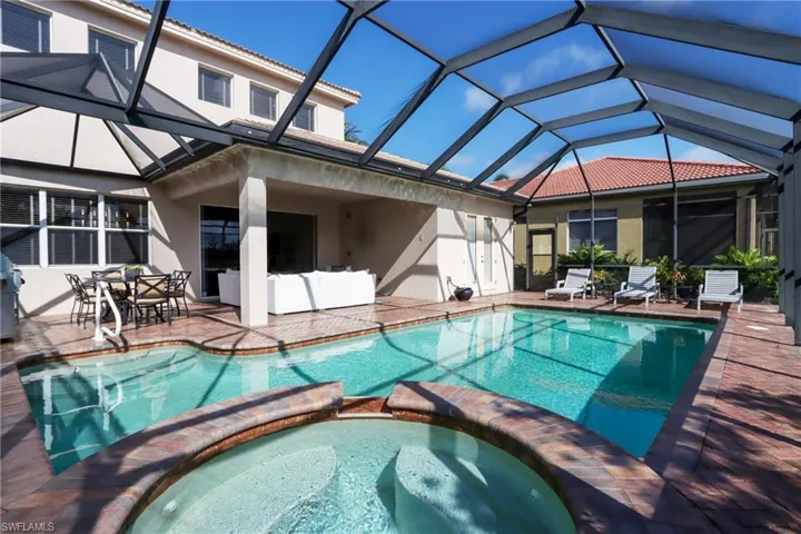 View of swimming pool with a pool with connected hot tub, a patio, and glass enclosure