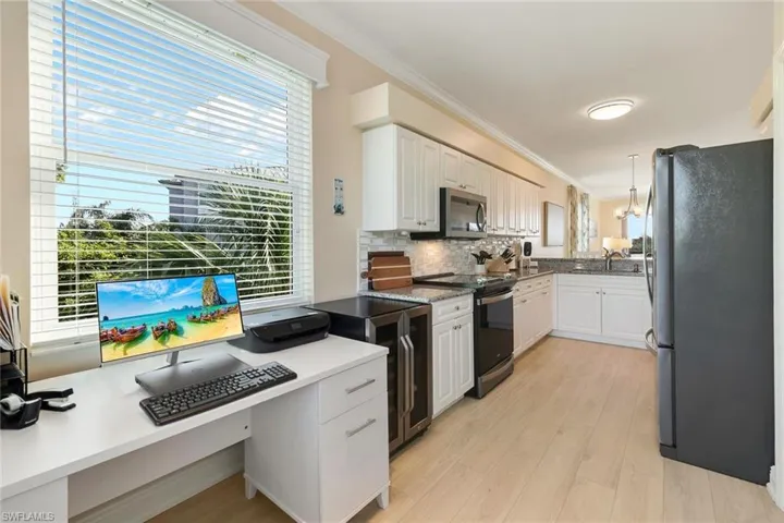 Kitchen featuring pendant lighting, appliances with stainless steel finishes, decorative backsplash, and white cabinets