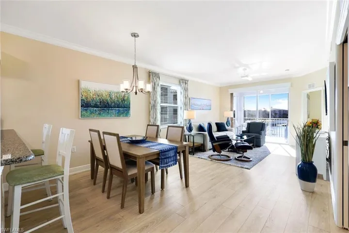 Dining area with crown molding, light hardwood / wood-style flooring, and a chandelier