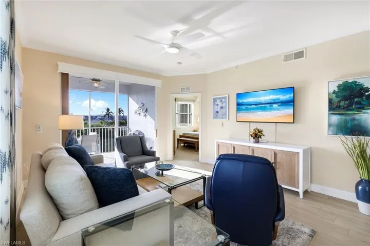 Living room with crown molding, ceiling fan, and light wood-type flooring