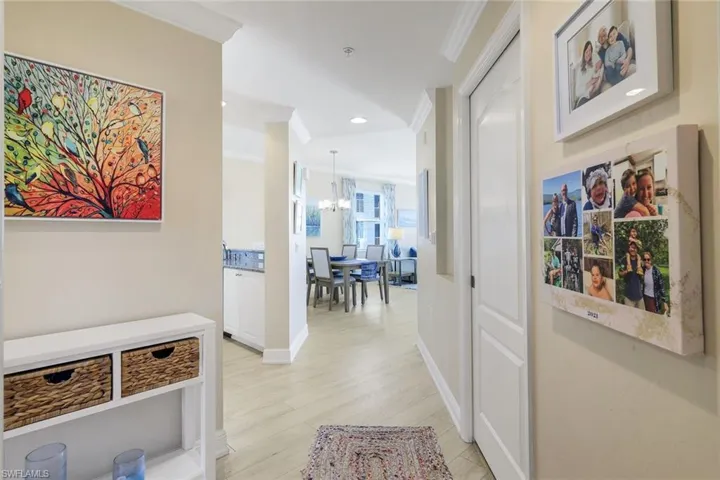 Hall featuring crown molding, an inviting chandelier, and light hardwood / wood-style floors