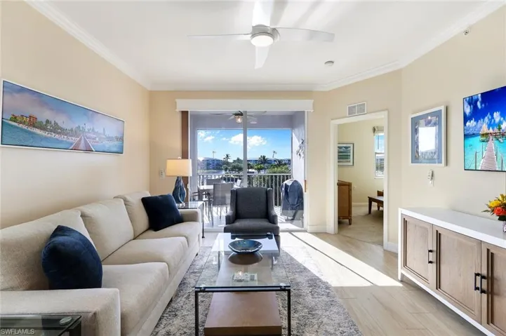 Living room with ceiling fan, ornamental molding, and light wood-type flooring