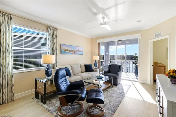 Living room with ceiling fan, ornamental molding, and light hardwood / wood-style floors