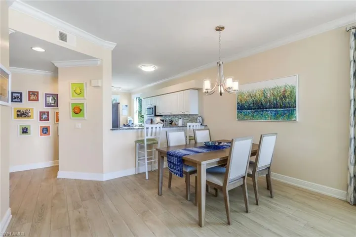 Dining room with crown molding, a chandelier, and light hardwood / wood-style floors
