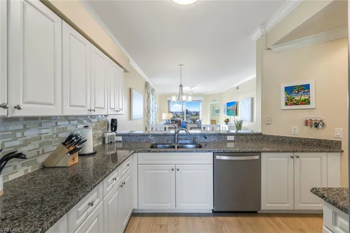 Kitchen featuring sink, stainless steel dishwasher, white cabinets, and dark stone counters