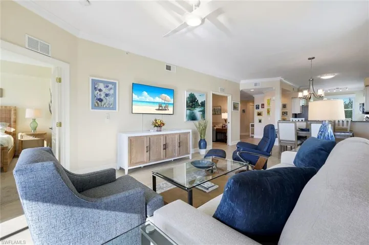 Living room with ornamental molding and ceiling fan with notable chandelier