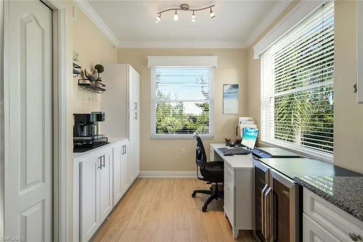 Home office with crown molding, a wealth of natural light, and light hardwood / wood-style floors