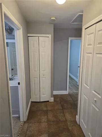Hallway with baseboards and dark tile patterned floors