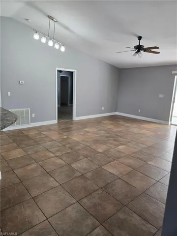Empty room with a ceiling fan and lofted ceiling