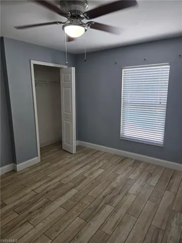 Unfurnished bedroom featuring wood finished floors, a closet, and a ceiling fan