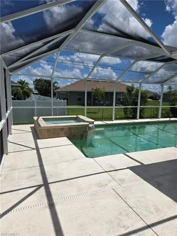 View of pool with a patio, a pool with connected hot tub, a lawn, and a lanai