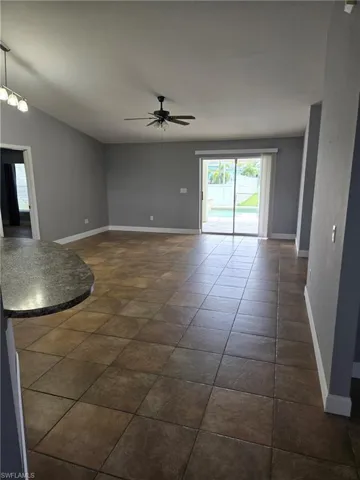 Unfurnished room with a ceiling fan and baseboards