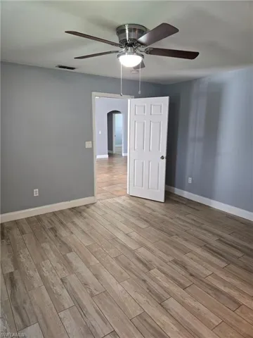 Spare room featuring a ceiling fan, arched walkways, and light wood-style flooring