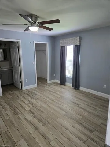 Unfurnished bedroom featuring light wood finished floors, a spacious closet, ceiling fan, and a closet