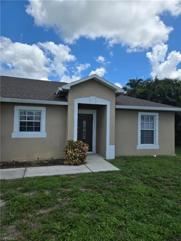 View of front of home featuring a front lawn, stucco siding, and roof with shingles